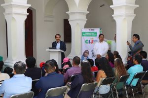 personas sentadas escuchando a un hombre que habla frente a ellos