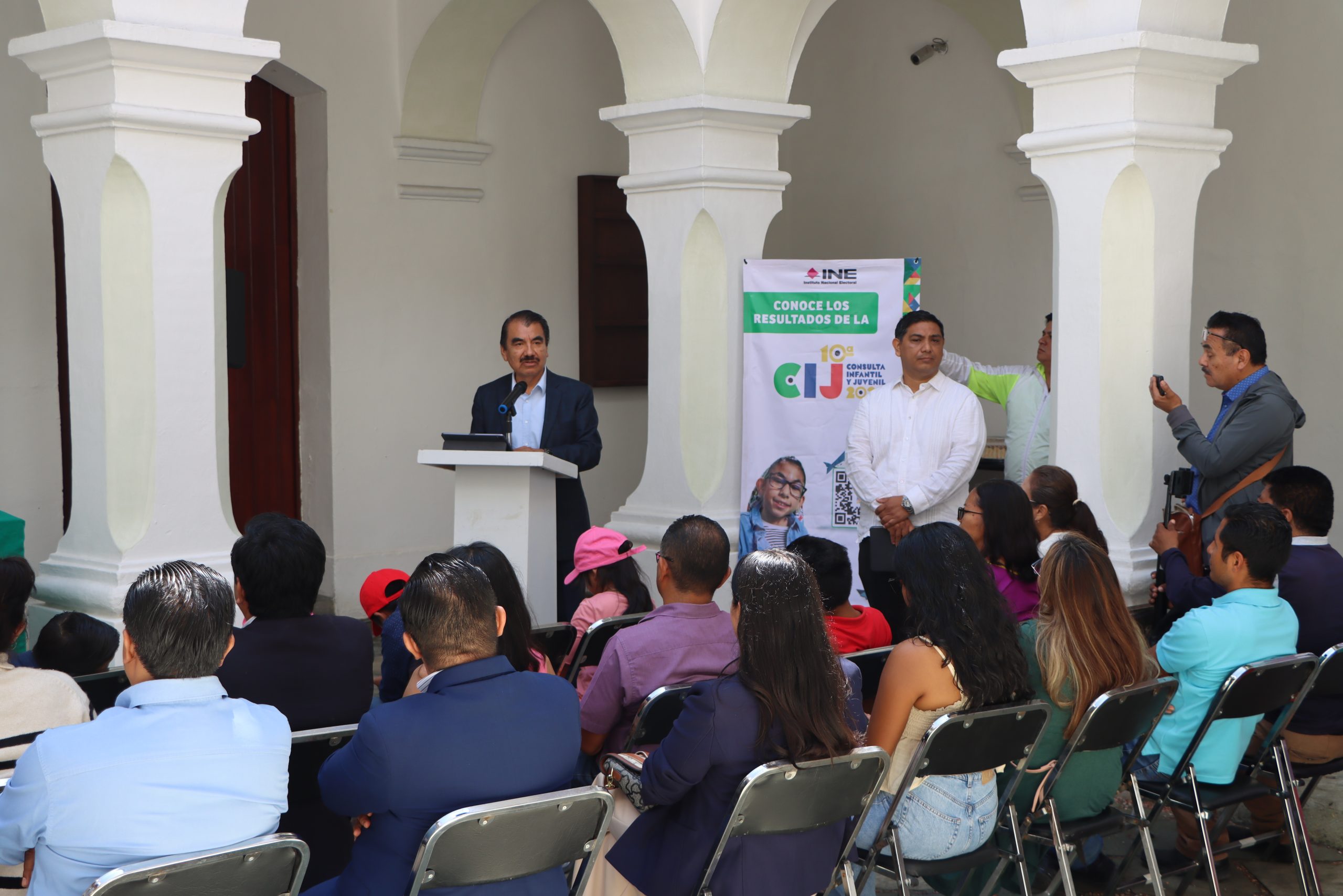 personas sentadas escuchando a un hombre que habla frente a ellos