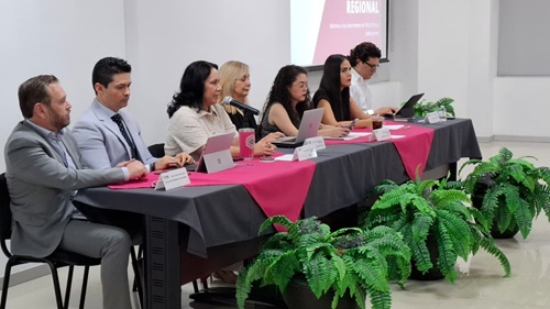 personas sentadas atrás de una mesa con mantel gris