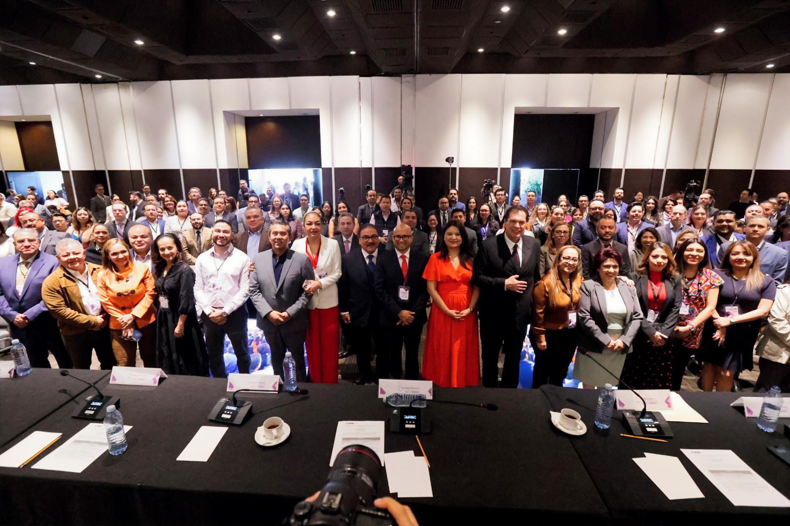 Imagen abierta en el salón del evento con las personas participantes posando para la foto.