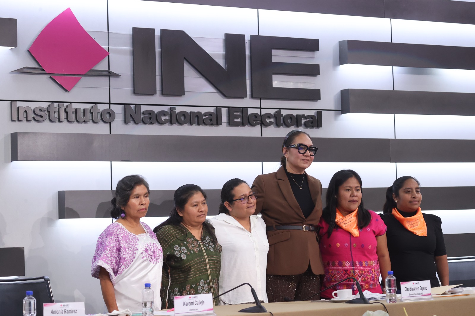 Personas participantes paradas en el estrado del auditorio del instituto.