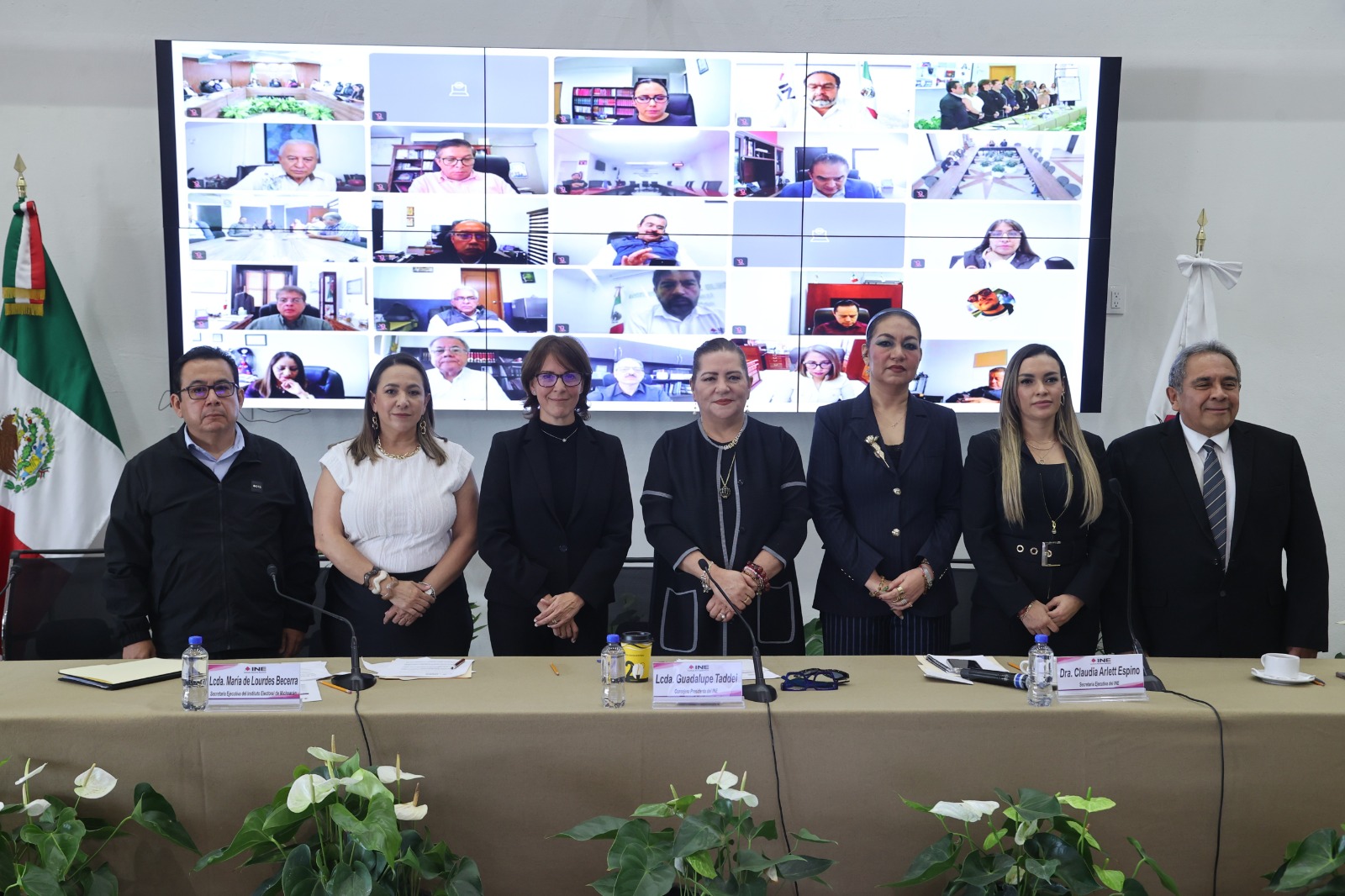 Personas participantes de pie en el estrado frente al público asistente.