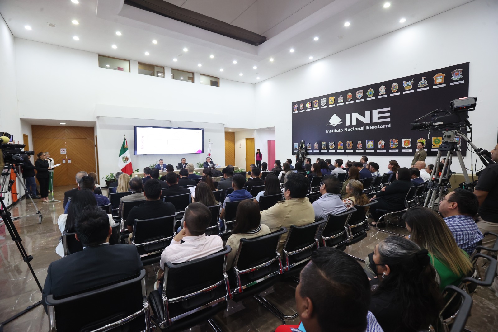 Imagen abierta en el lobby del instituto con las personas participantes sentadas al frente de la audiencia.