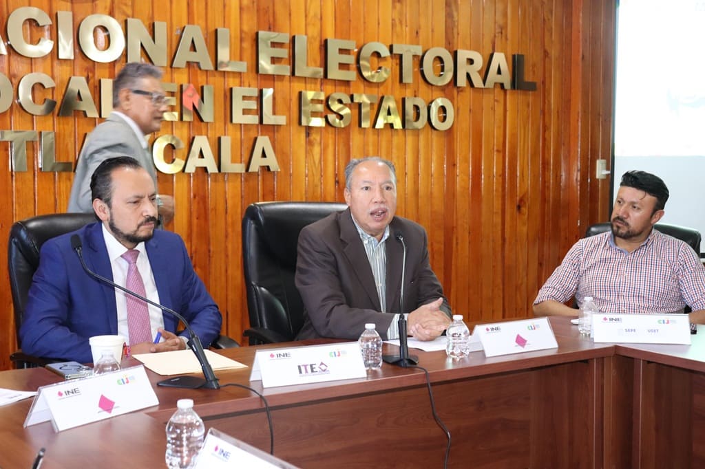tres hombres sentados en frente a una mesa con micrófonos