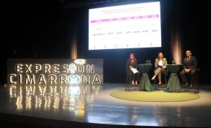 tres personas sentadas a un costado de un letrero luminoso