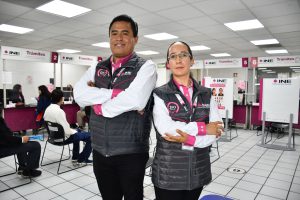 dos personas de pie con brazos cruzados y chaleco negro