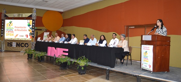 Personas sentadas escuchando a una mujer de pie en un pódium