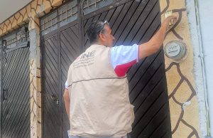 hombre con chaleco del INE tocando un timbre en una casa