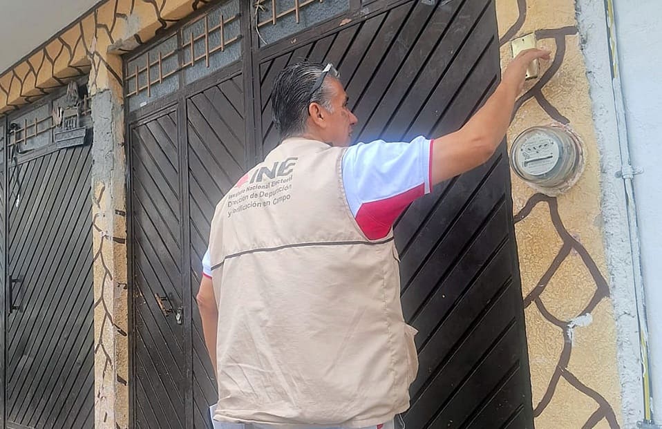 hombre con chaleco del INE tocando un timbre en una casa