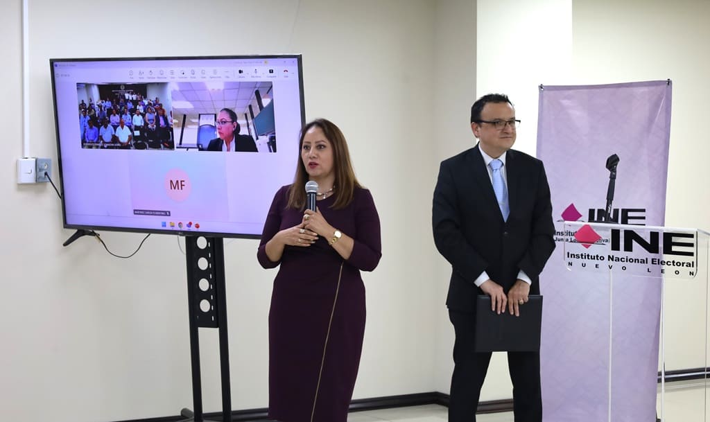 Dos personas de pie frente a una pantalla de televisión