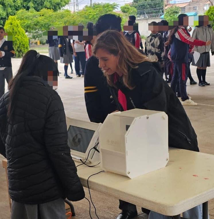 mujer ayudando a una estudiante a usar una urna electrónica