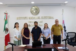 personas de pie frente a unas letras doradas