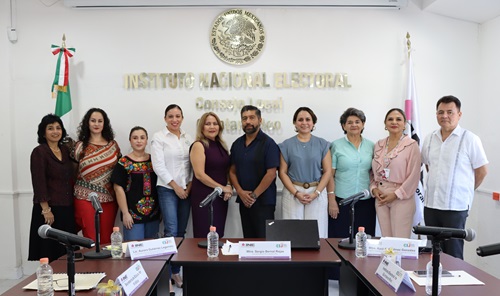 personas de pie frente a unas letras doradas