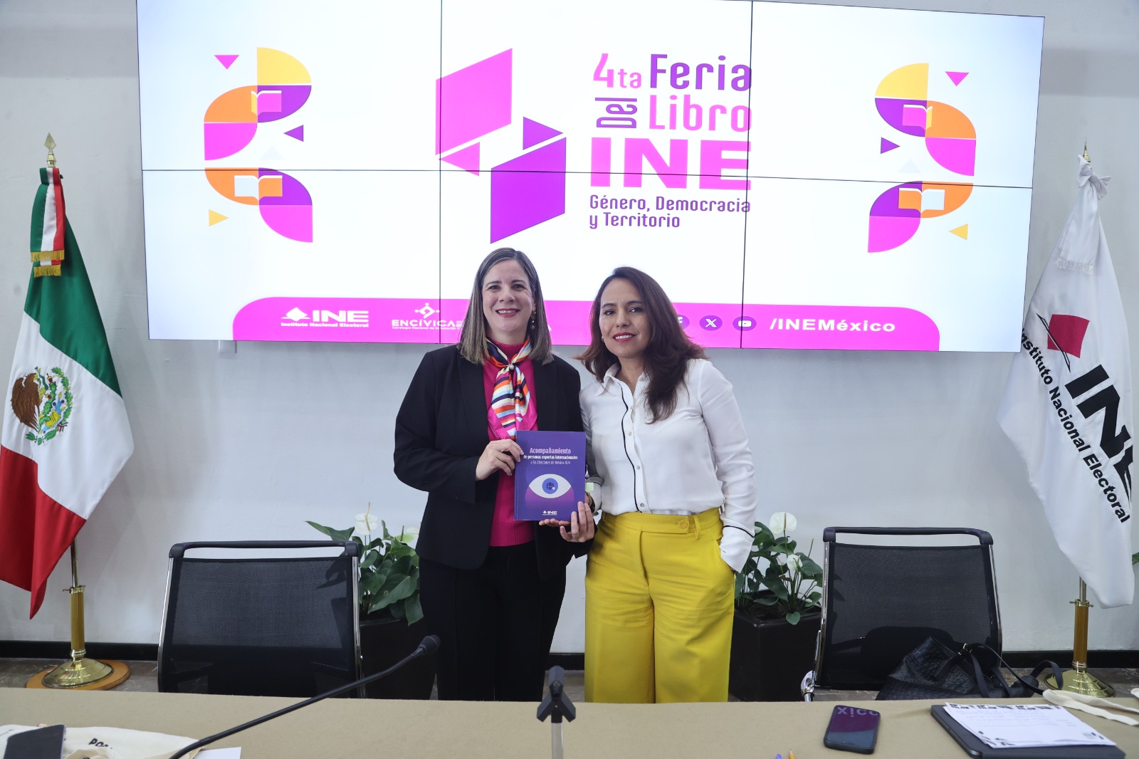 Persona participantes paradas en el lobby con el libro en las manos.