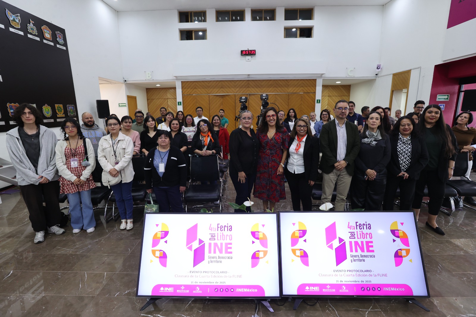 Persona participantes y público asistente paradas en el lobby del Instituto posando para la foto.
