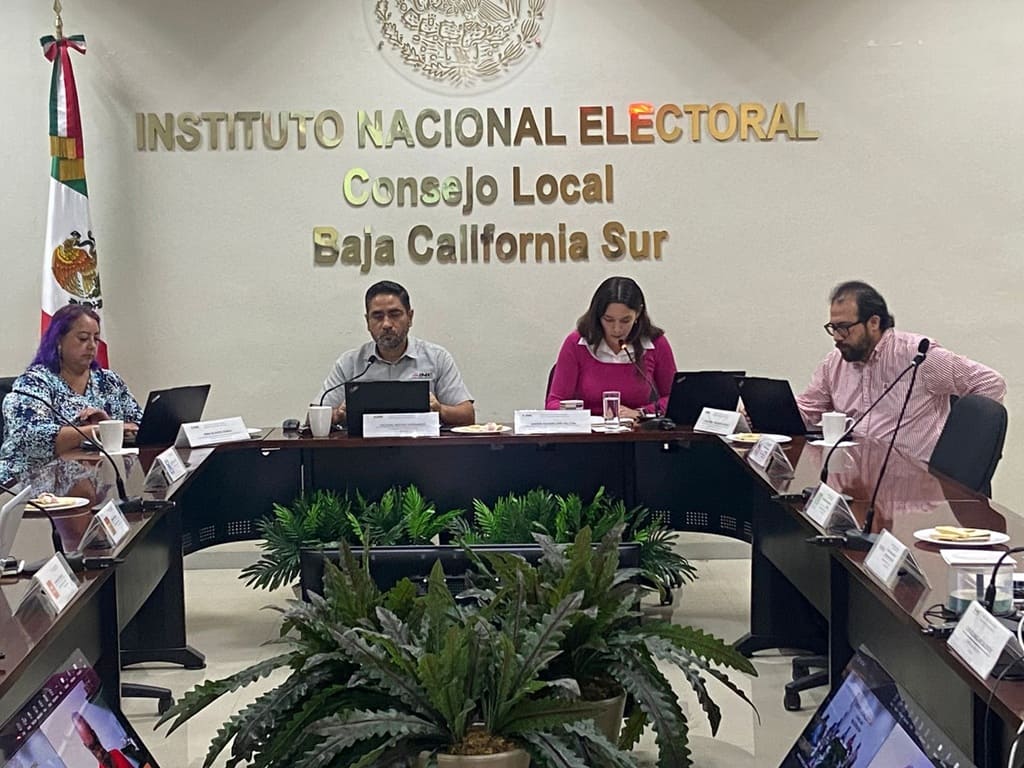 varias personas sentadas frente a una mesa con micrófonos