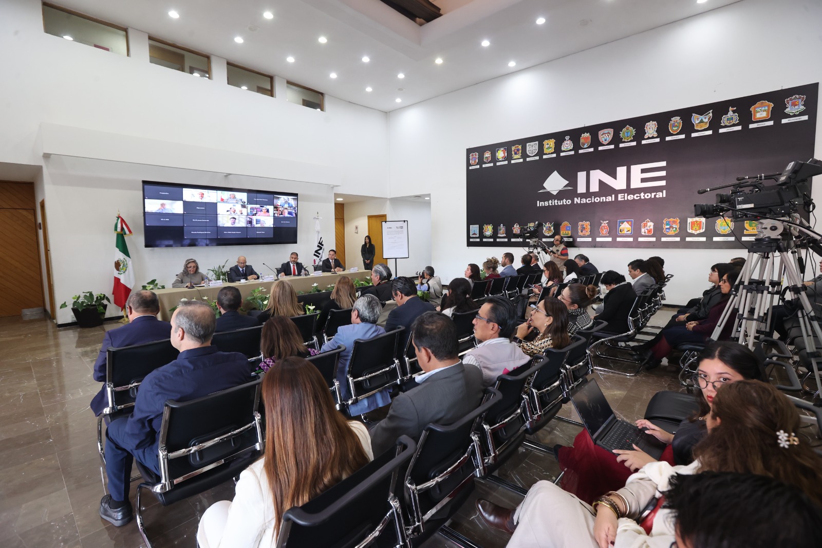 Persona participantes sentadas en el estrado en el lobby del instituto durante su participación en el evento.