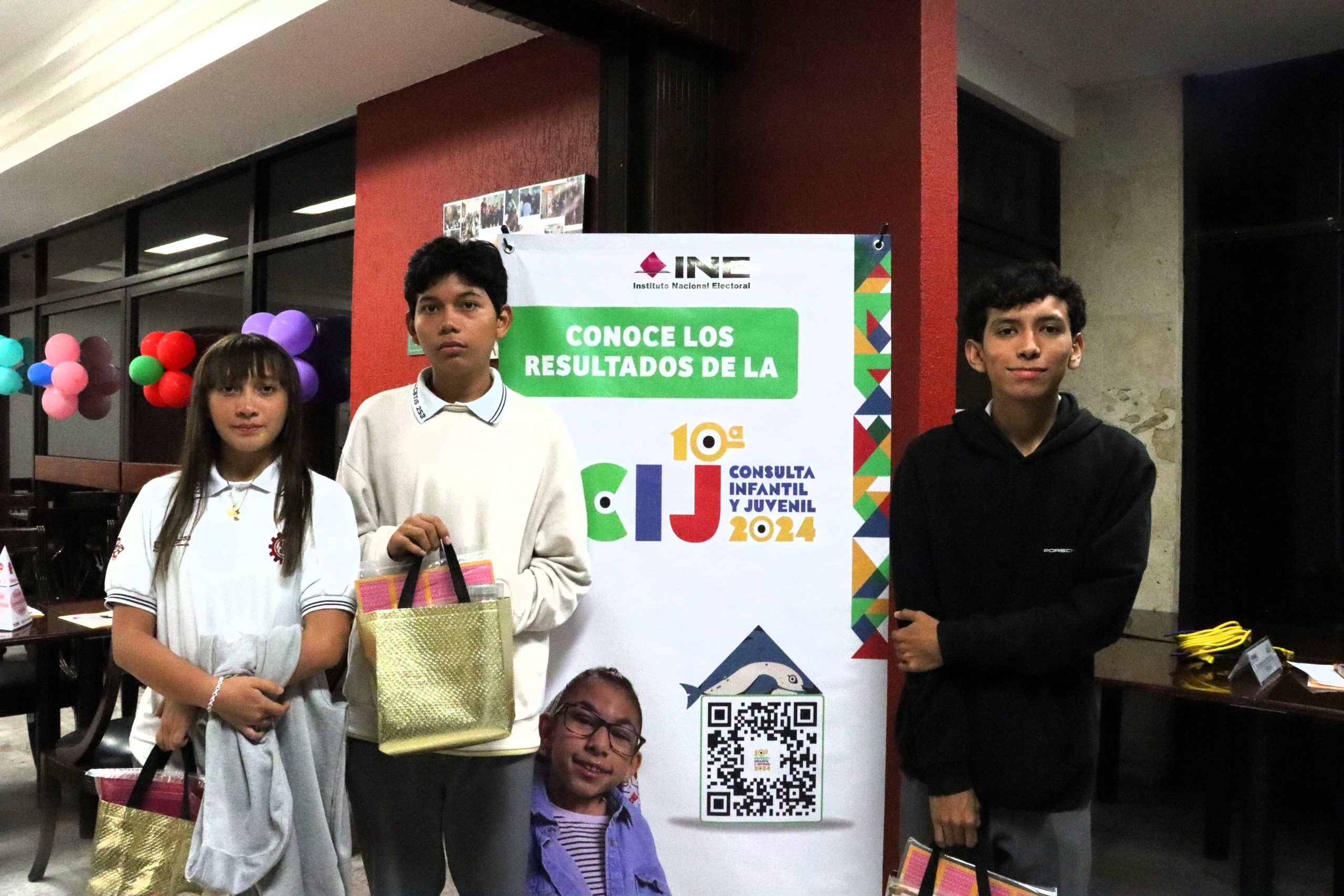 Adolescentes de pie a un lado de un cartel de colores