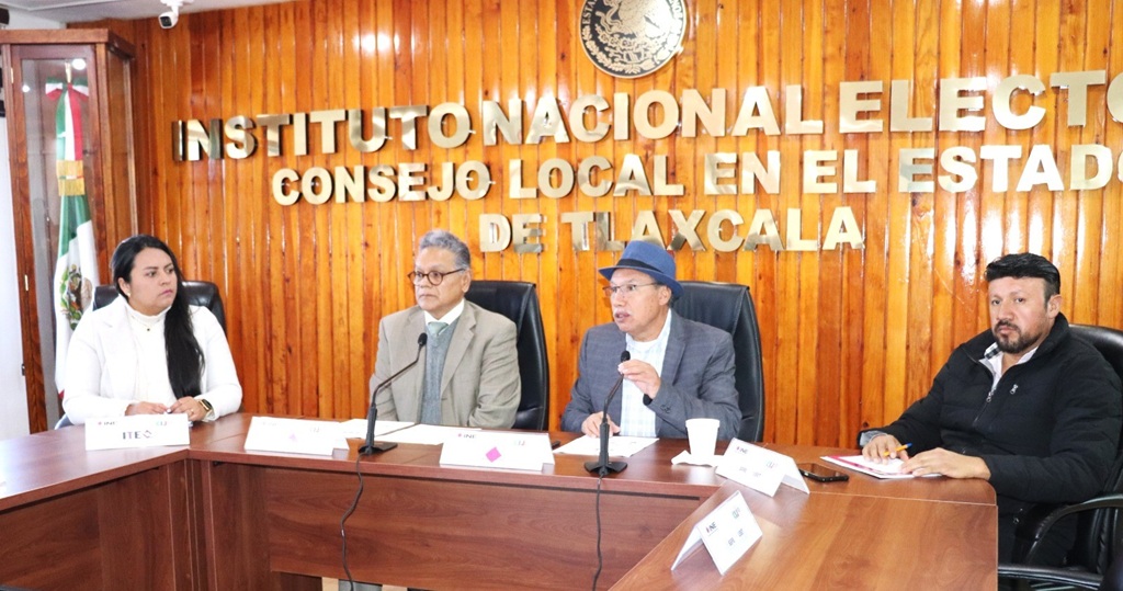 cuatro personas sentadas frente a una mesa con micrófonos