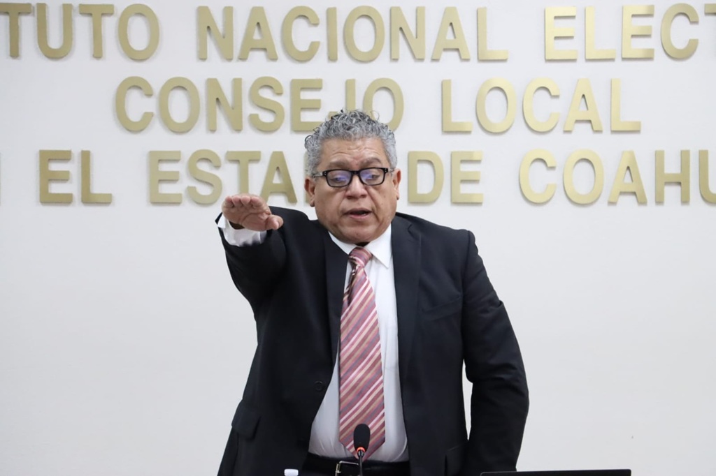 un hombre cabello cano de pie con el brazo derecho al frente
