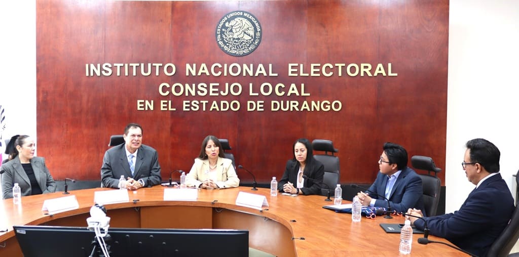 tres mujeres y tres hombres sentados en una mesa ovalada color café