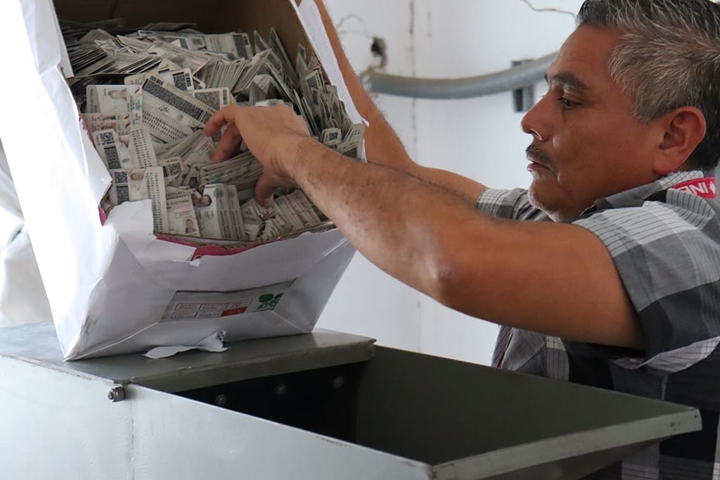 Un hombre sacando credenciales sin validez de una caja