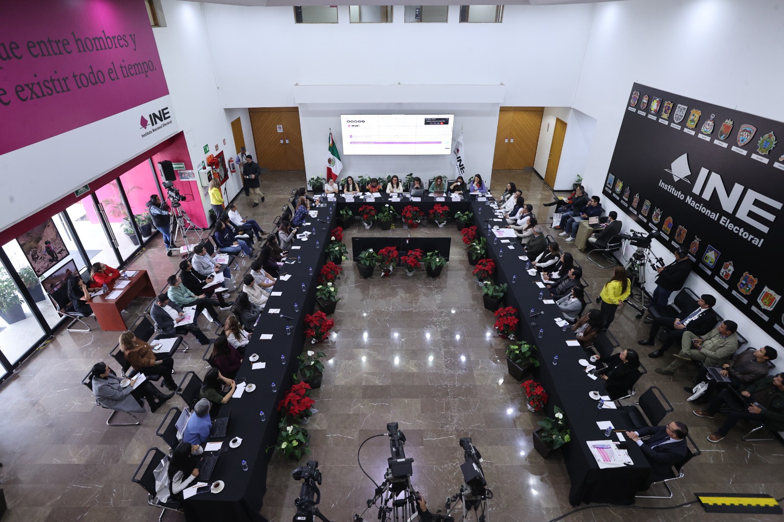 Toma abierta del Lobby del instituto persona participantes sentadas frente al público asistente.