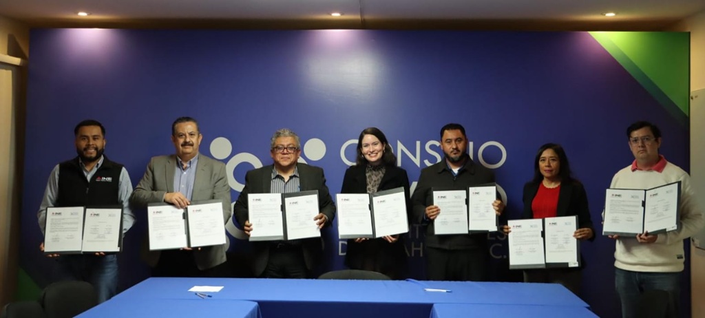 cinco hombres y dos mujeres de pie, cada uno sostiene un documento