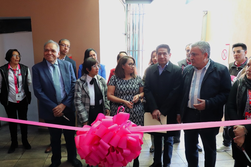 varias personas de pie atrás de un listón rosa con un moño