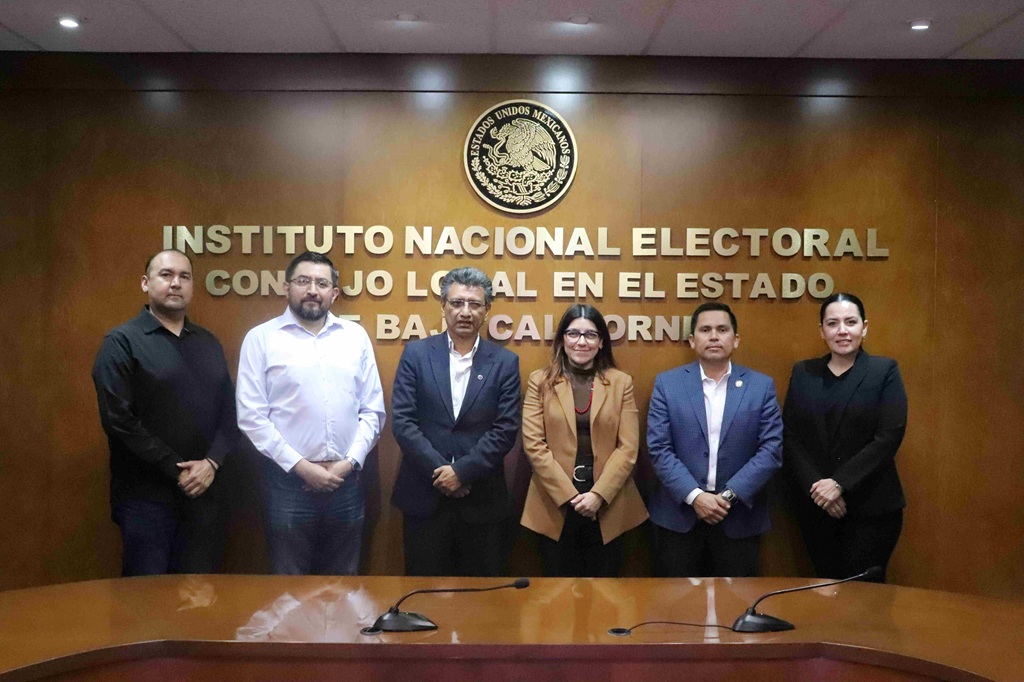 dos mujeres y cuatro hombres de pie mirando al frente