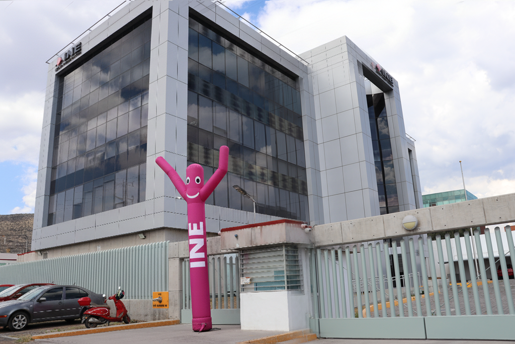 Edificio de cuatro pisos con un muñeco rosa que se mueve con el aire afuera