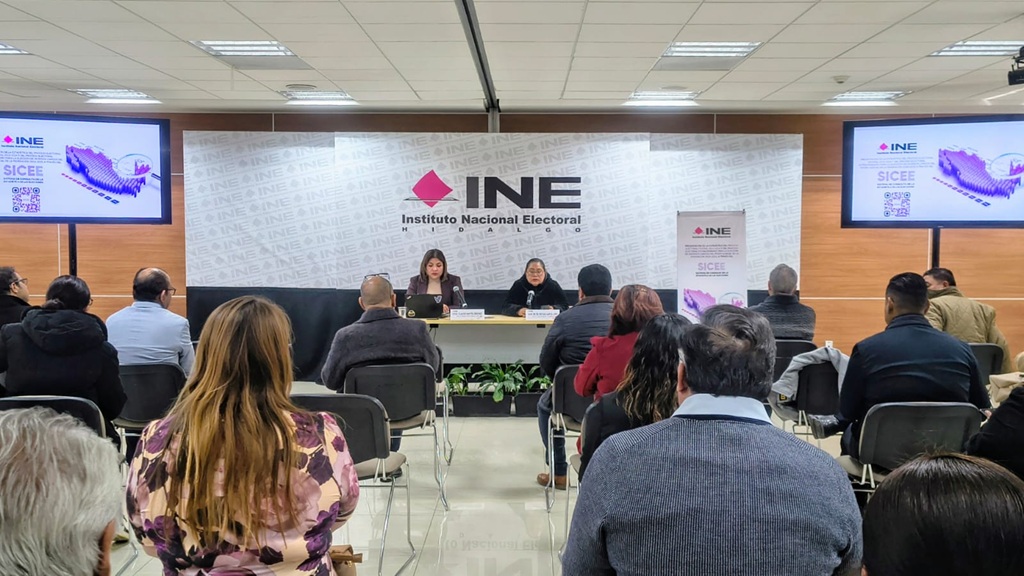personas escuchando a dos mujeres sentadas al frente