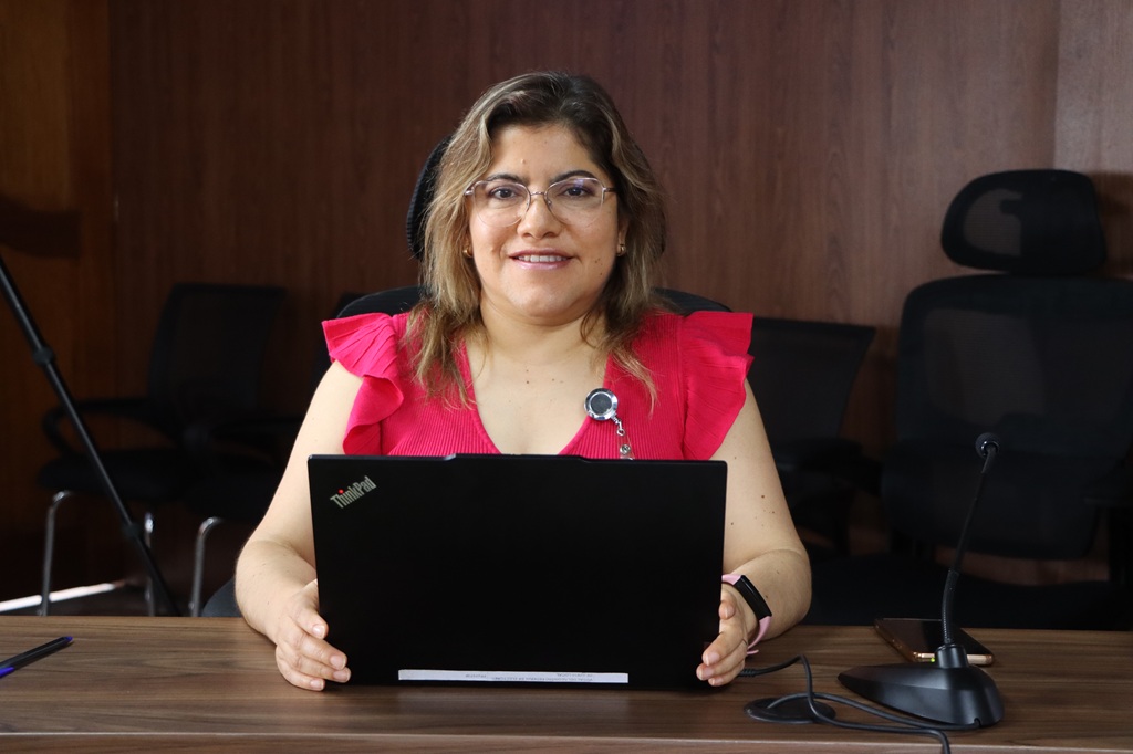 una mujer sonriendo sentada frente a una computadora portátil