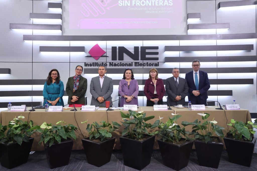 Personas participantes paradas en el estrado del auditorio posando para la foto.