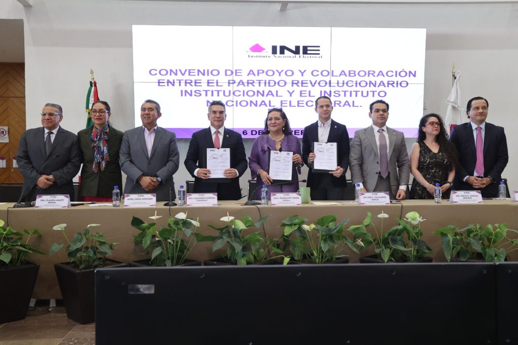 Personas participantes paradas en el estrado sosteniendo el documento posando para la foto.