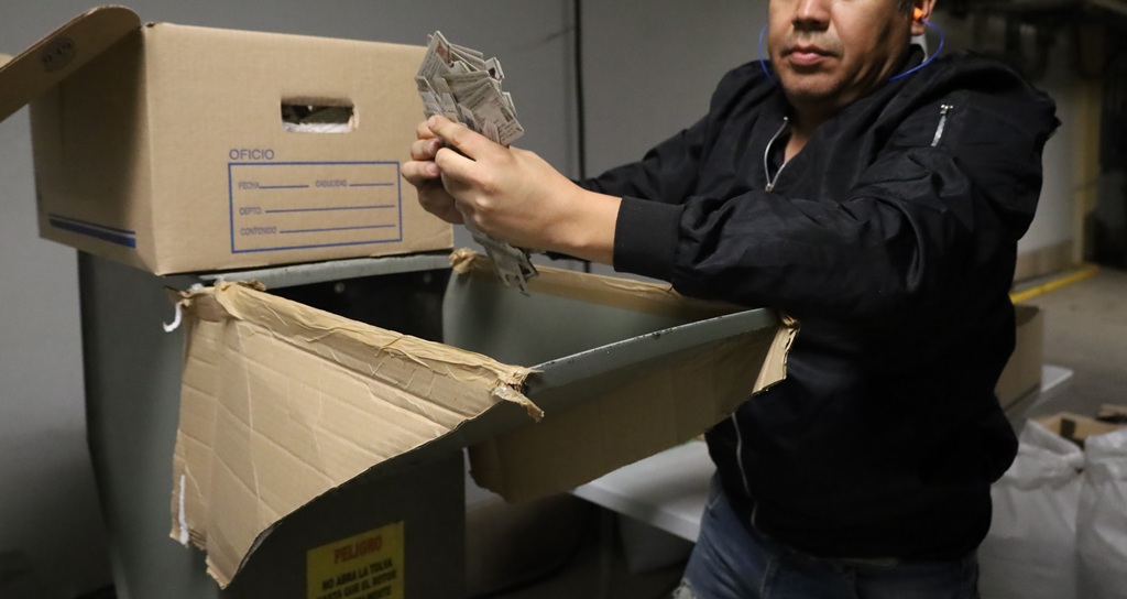 un hombre colocando credenciales para votar sin validez en maquina trituradora