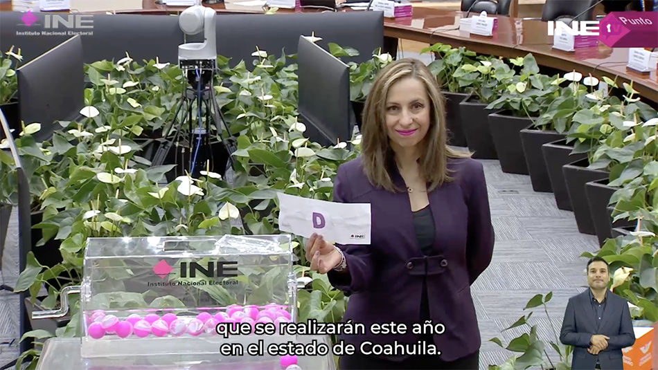Edecán sosteniendo letrero con la Letra "D"
