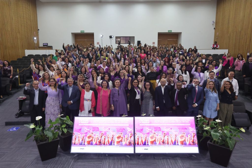 Personas participantes y público asistente paradas en el auditorio del Instituto posando para la foto oficial.
