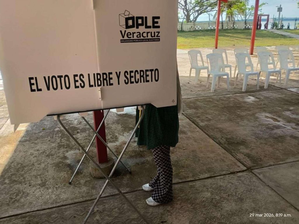 Persona votando dentro de la mampara.