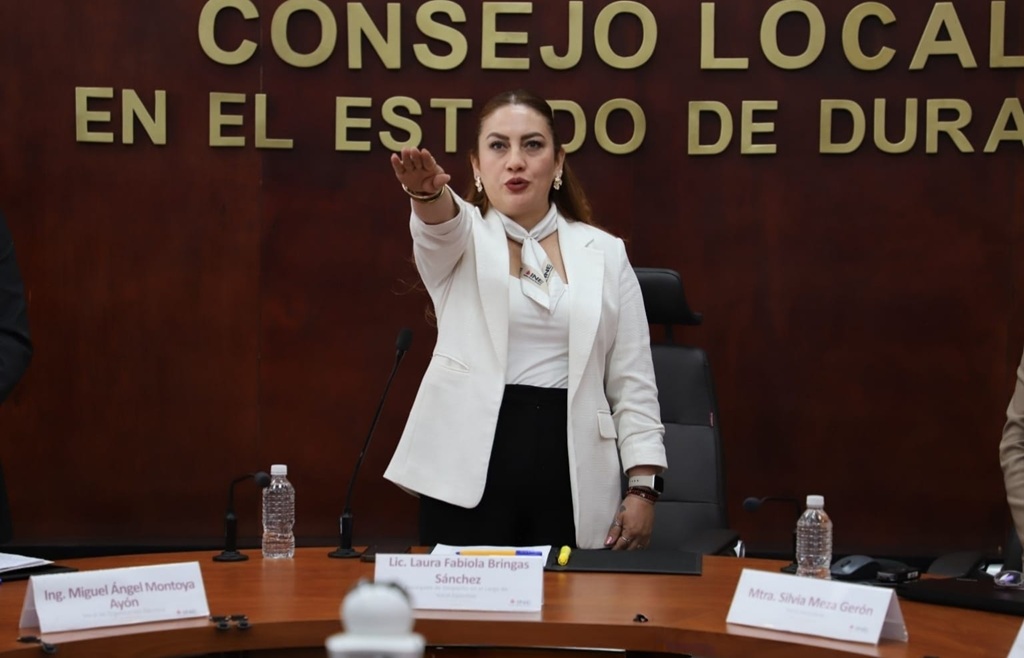 mujer con saco blanco de pie y el brazo derecho extendido al frente