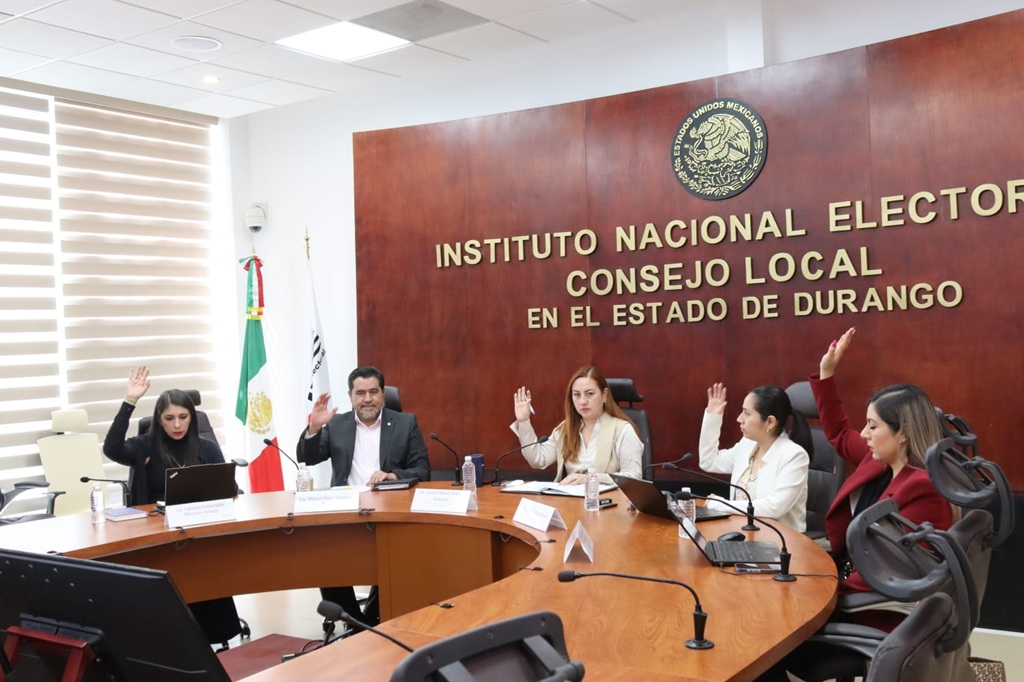 Cuatro personas sentadas votando a mano alzada