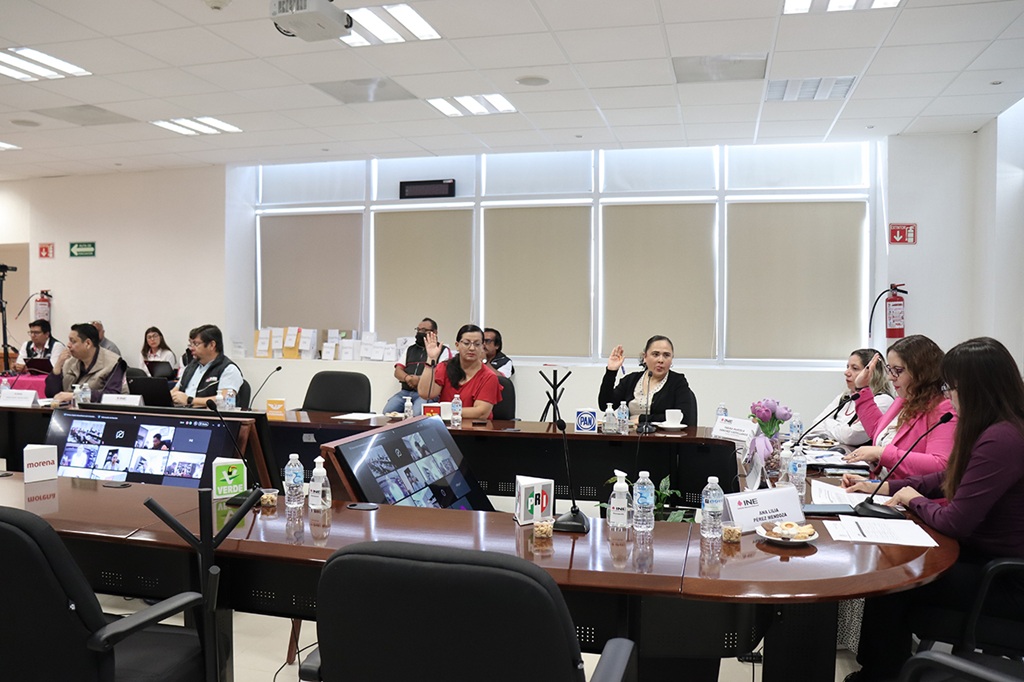 varias personas sentadas alrededor de una mesa votando a mano alzada