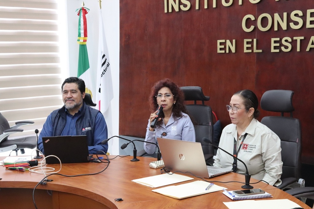 tres personas sentada frente a una mesa con micrófonos