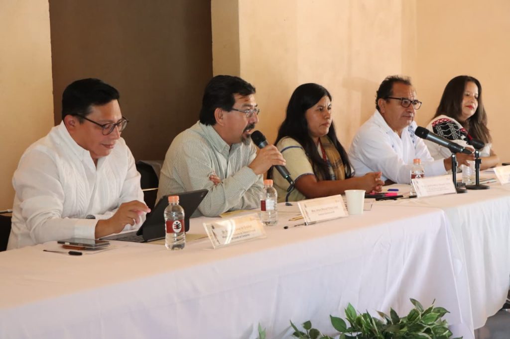 Personas participantes sentadas en el estrado.