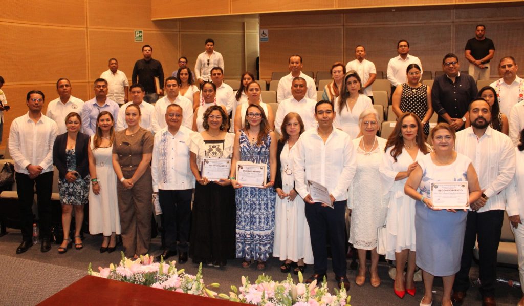 Personas participantes y púbico parados en el salón posando para la foto.