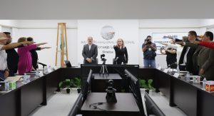 varias personas alrededor de una mesa rectangular con el brazo derecho extendido al frente