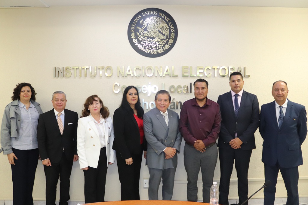 ocho personas de pie abajo del escudo nacional y letras doradas