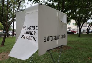 mampara blanca en un parque con leyenda en letras negras el voto es libre y secreto