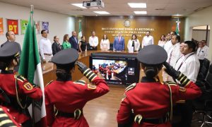 una sala de juntas con una escolta de mujeres vestidas de rojo y portando la bandera nacional
