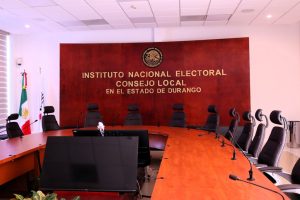 sala de juntas con sillas y micrófonos en la mesa